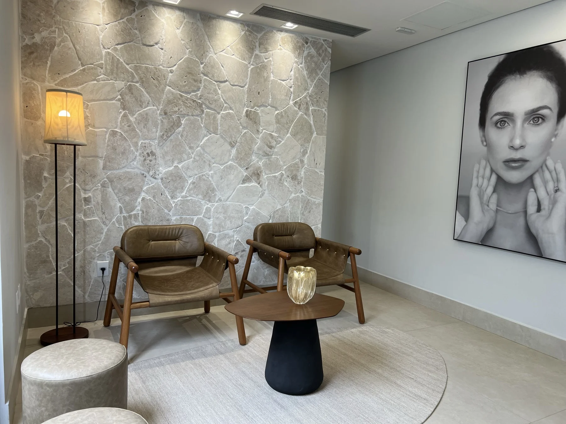 Lounge de espera — couro creme e parede de pedra